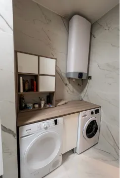 Bathroom equipped with a washing machine, tumble dryer, wall cabinet, and water heater. - image 16
