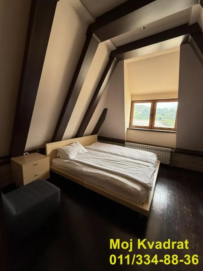 Potkrovna spavaća soba sa bračnim krevetom, krovnim gredama i prozorom sa pogledom.