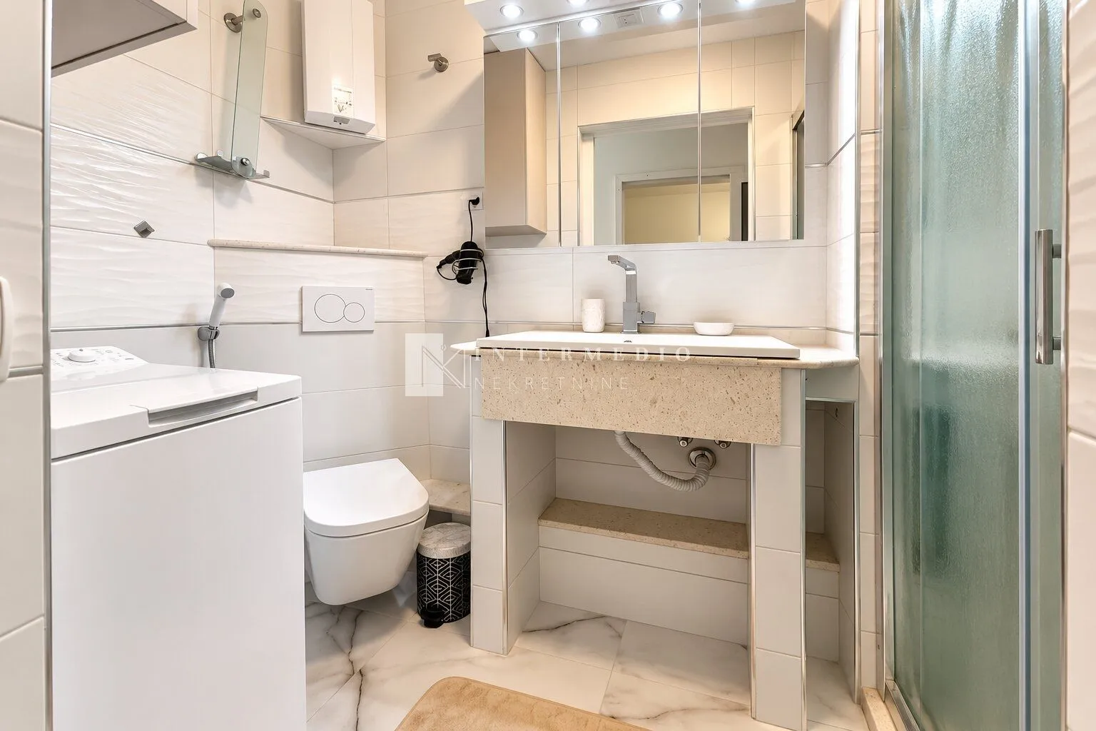 Svijetlo moderno kupatilo sa umivaonikom, WC šoljom i tuš kabinom.