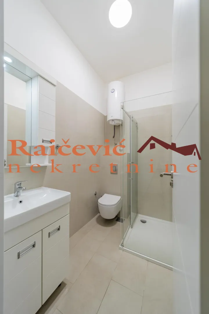Moderno kupatilo sa tuš kabinom, umivaonikom i wc šoljom.