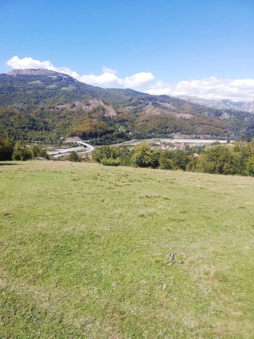 Prostrani zeleni plac sa pogledom na planine.