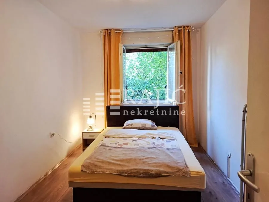 Small bedroom with a double bed, yellow curtains, and a window overlooking greenery.