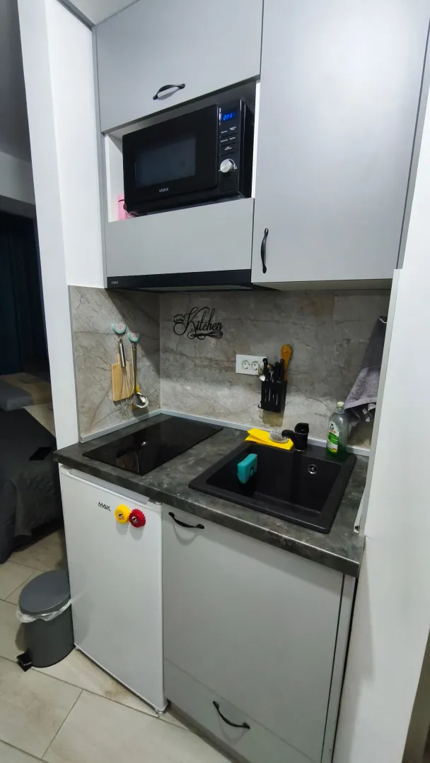 Small kitchen with grey cabinets, built-in cooktop, and a microwave.
