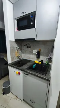 Small kitchen with grey cabinets, built-in cooktop, and a microwave. - image 2