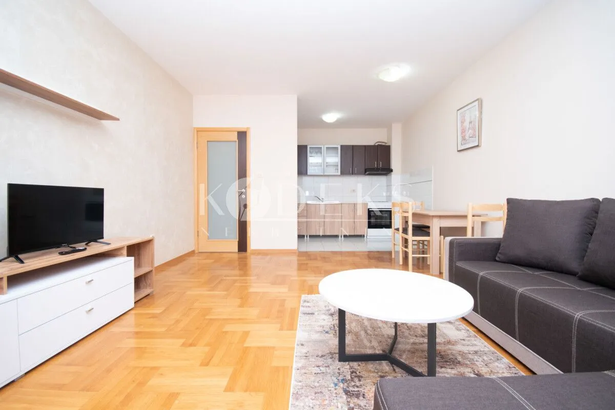 Living room with a sofa, TV, and an adjoining dining area.