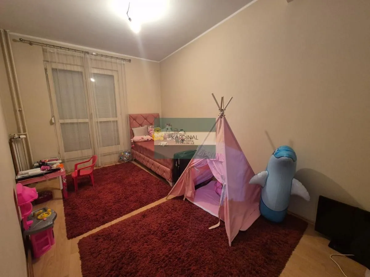 Dečja soba sa krevetom, igračkama i izlazom na terasu.