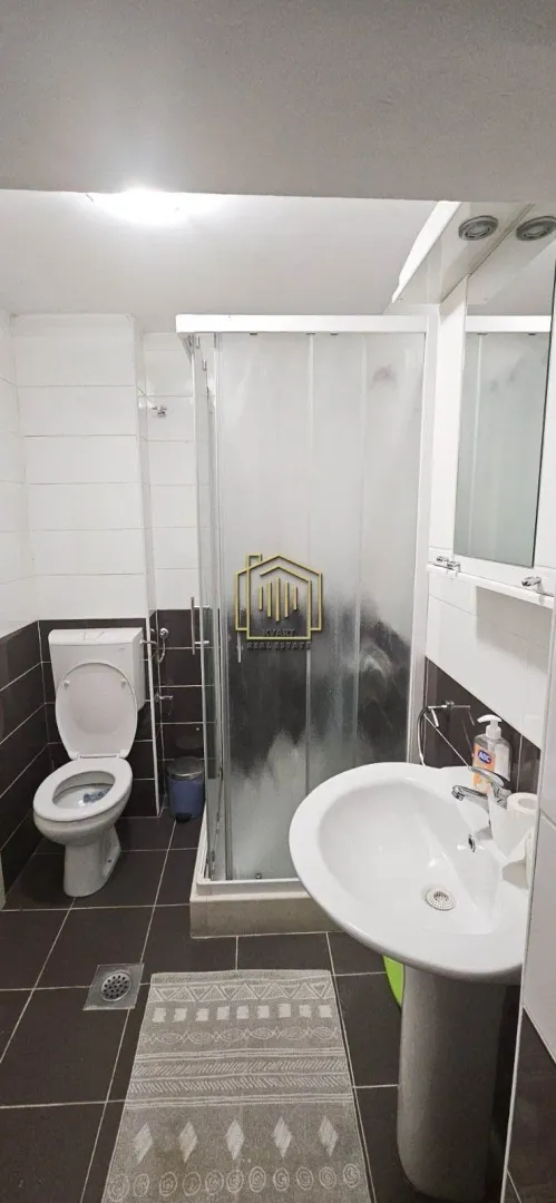 Compact bathroom with a shower cabin, washbasin, and toilet.
