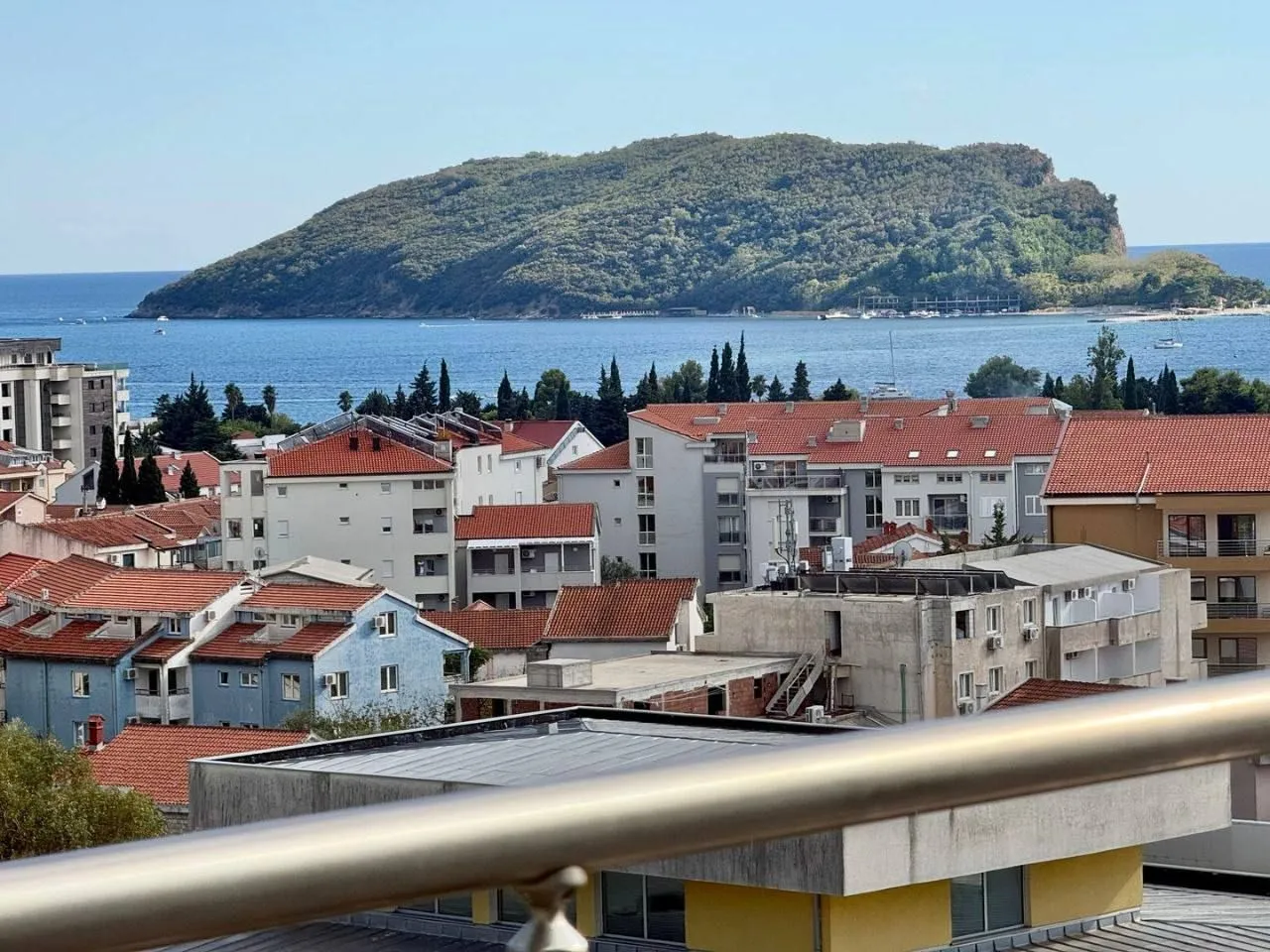 Pogled sa terase na grad i more sa ostrvom u pozadini.