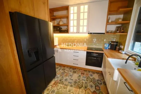 Kuhinja opremljena drvenim elementima, crnim frižiderom i šarenim podnim pločicama. - image 4