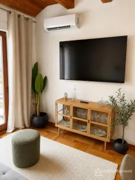 Dnevna soba sa televizorom, komodom, klima uređajem i drvenim podom. - image 3