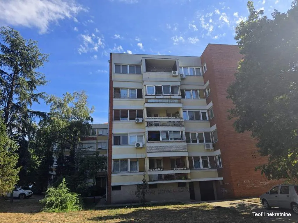 Pogled na spoljašnjost stambene zgrade sa terasama i zelenilom.