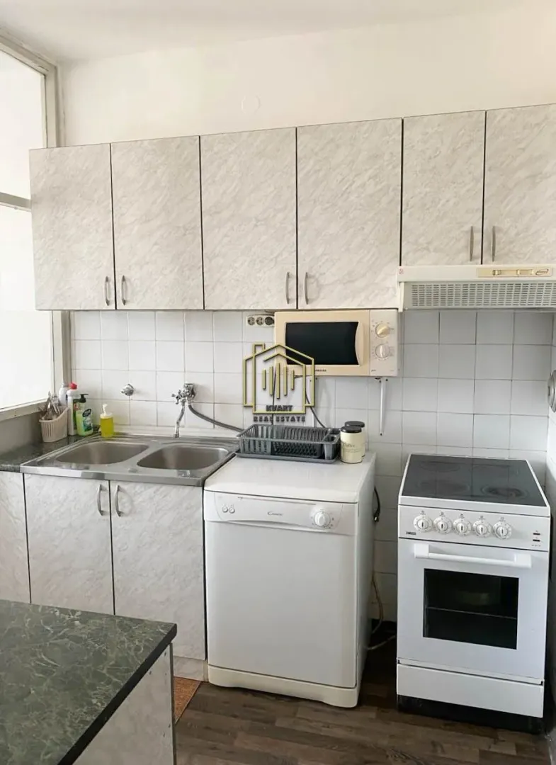 Compact kitchen with a sink, stove, dishwasher, and upper cabinets.