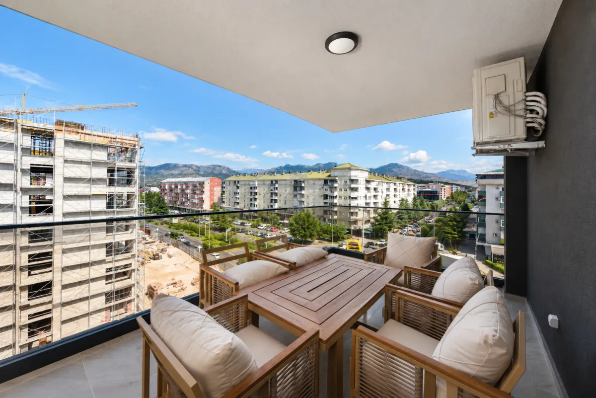 Covered terrace with wooden table and chairs and city view.