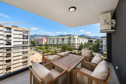 Covered terrace with wooden table and chairs and city view. - image 7