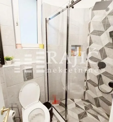 Moderno opremljeno kupatilo sa tuš kabinom i sanitarijama.
