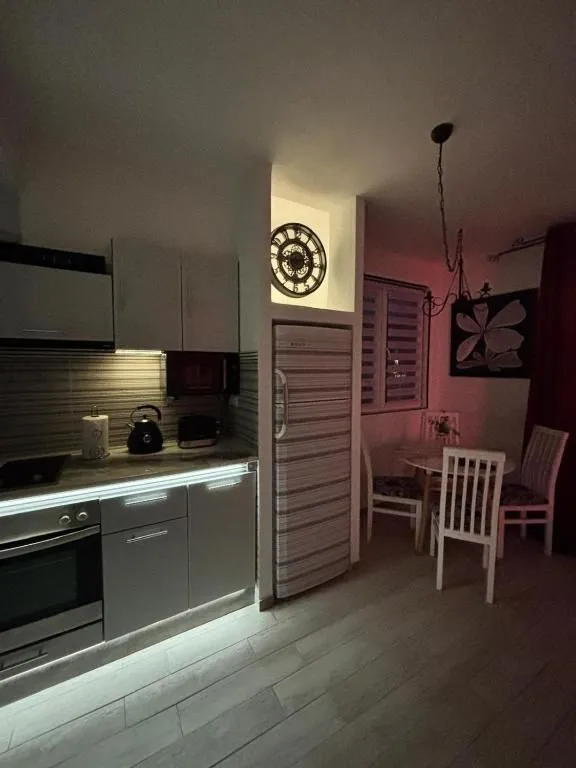 Kuhinja sa elementima i trpezarijskim stolom u uglu.