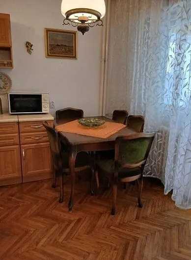 Trpezarijski sto sa stolicama u kuhinji sa drvenim elementima.
