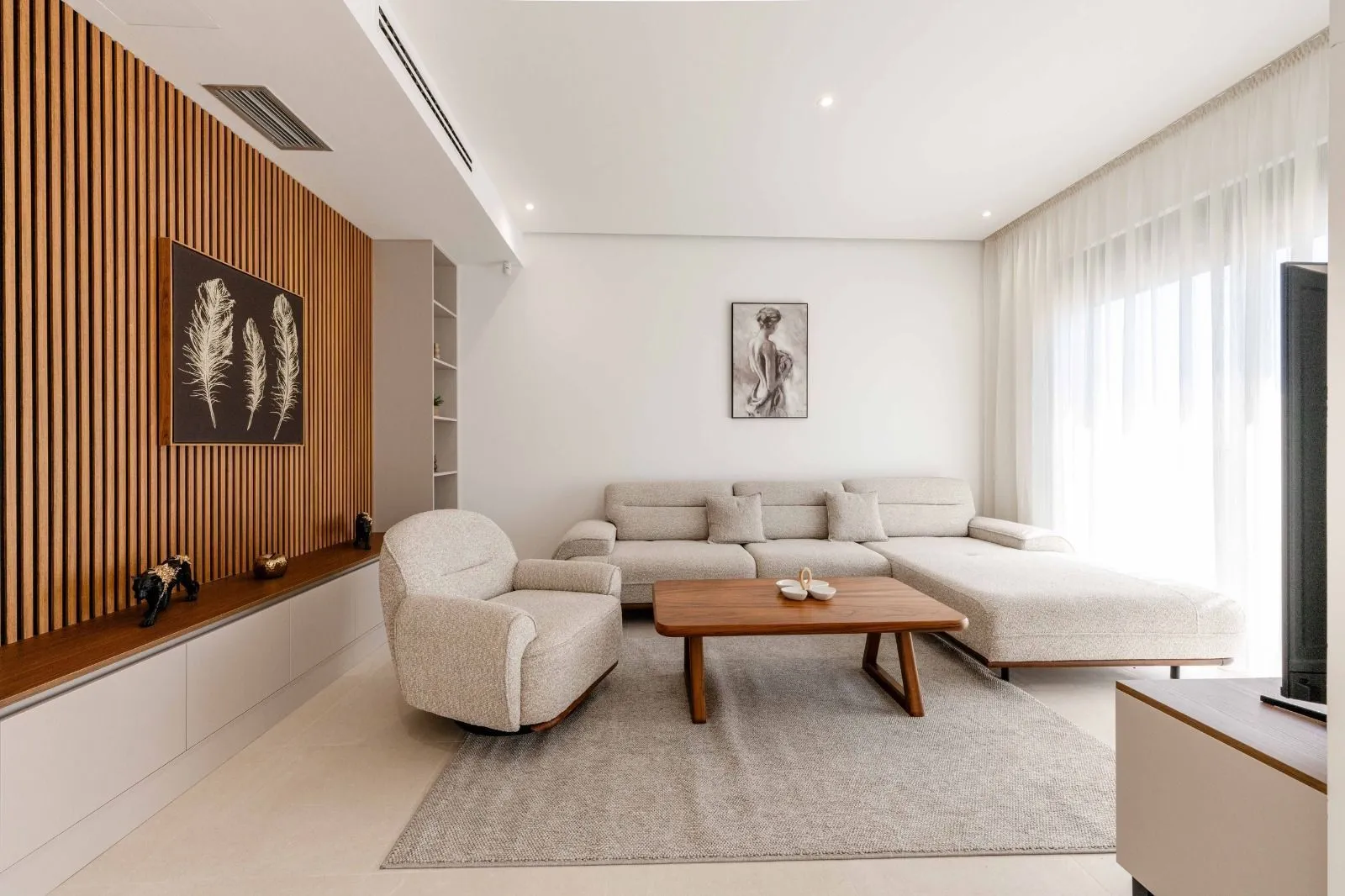 Living room with a sectional sofa, armchair, and wooden wall panels.