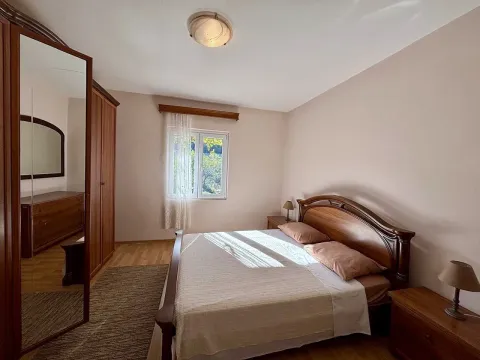 Spacious bedroom with a double bed, wooden wardrobe with a mirror, and nightstands. - image 6