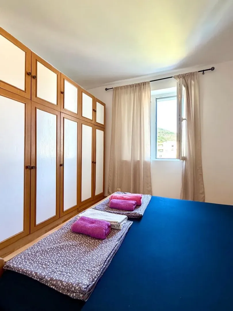 Bedroom with a bed, a large wooden wardrobe, and a window.