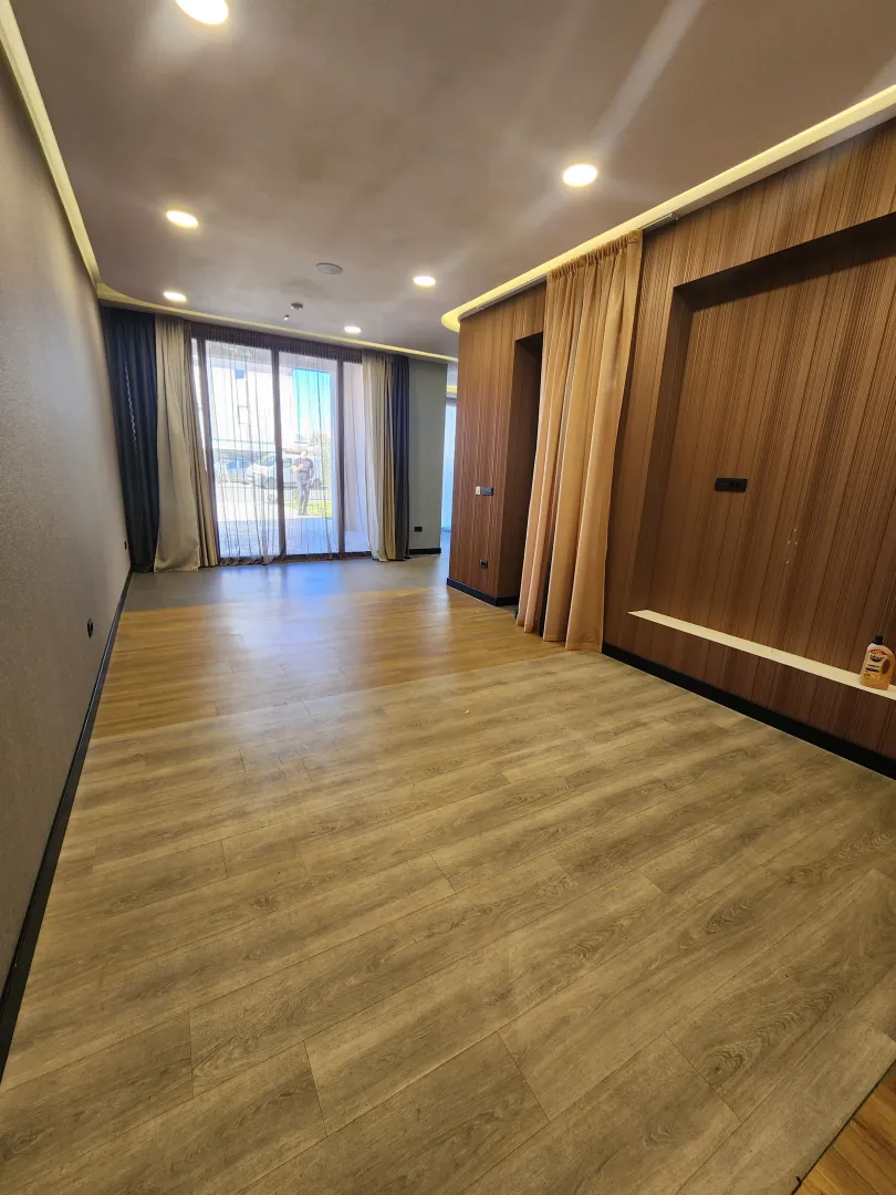 Empty living room with wood wall panels and access to the terrace.