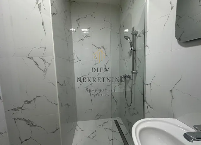 Modern bathroom with a walk-in shower lined with marble tiles.