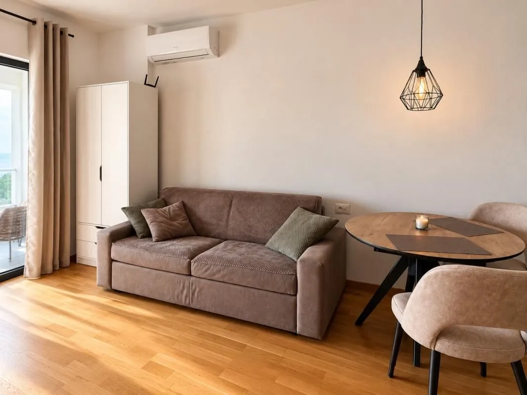 Living room with a sofa, dining table, and access to the terrace.