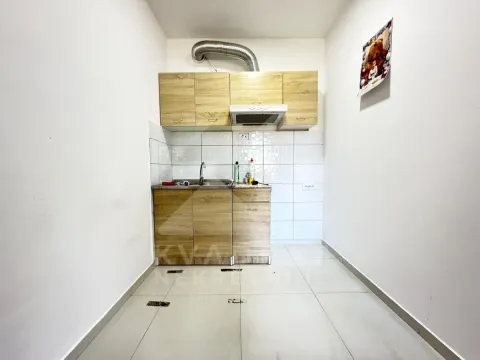 Small kitchen with wooden cabinetry and white wall tiles. - image 4