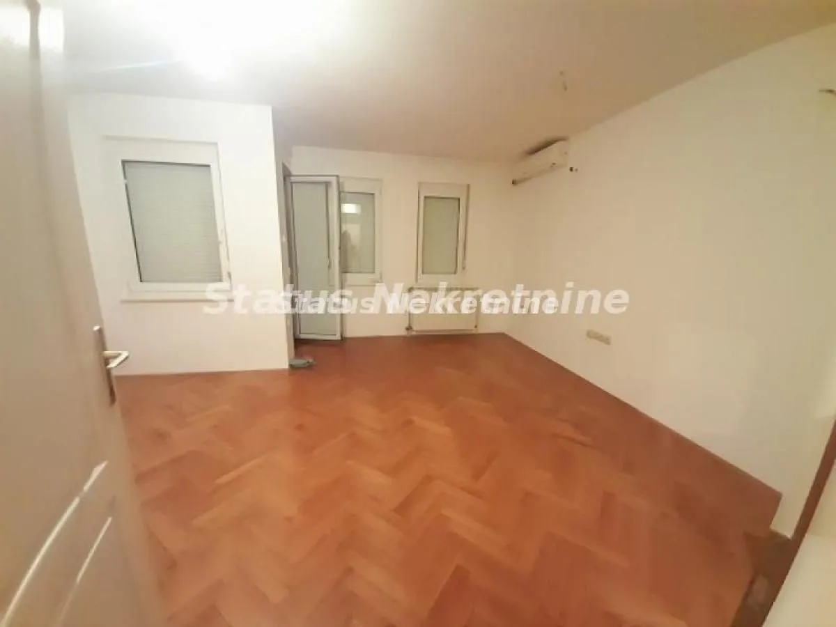 Prazna soba sa parketom i belim zidovima.