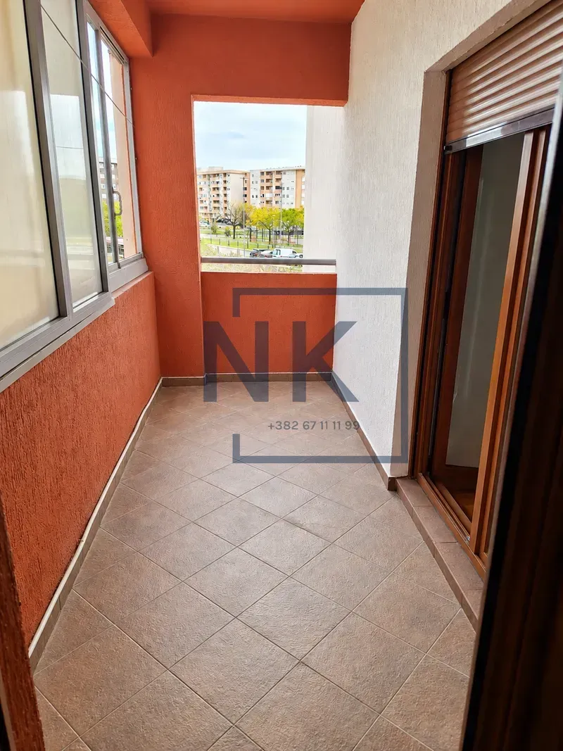 Natskriveni balkon sa popločanim podom i pogledom na grad.