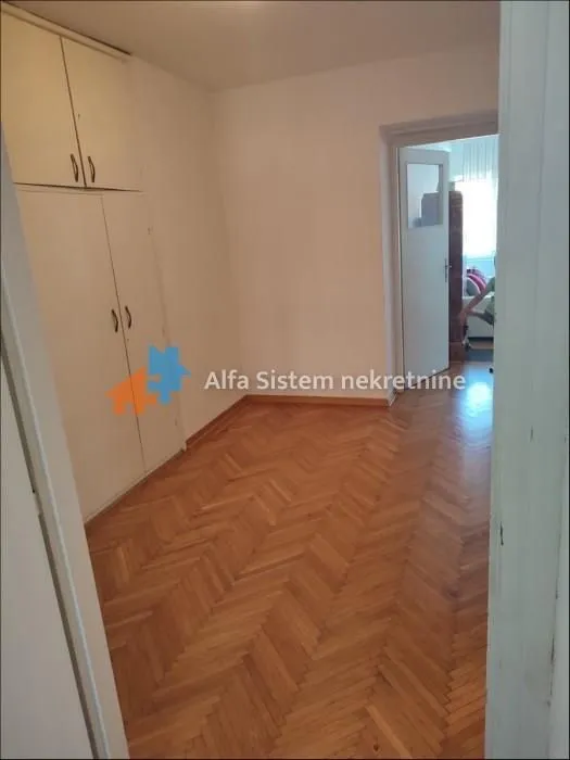Prazna soba sa ugradnim ormarom i parketom na podu.