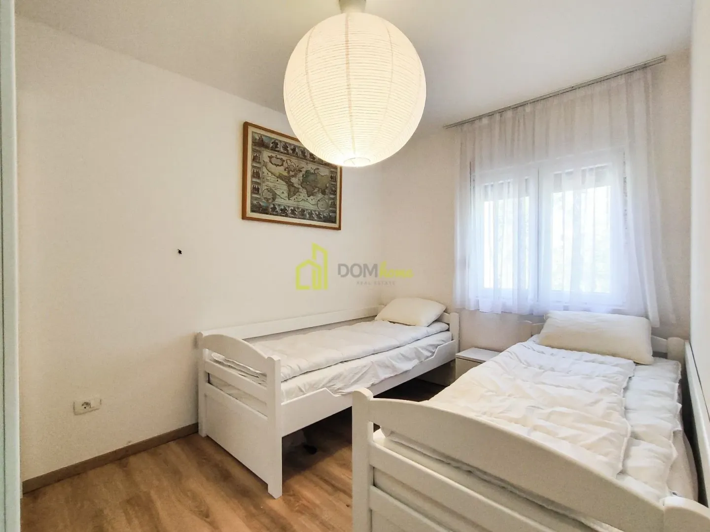 Bedroom with two white single beds and a large round ceiling lamp.