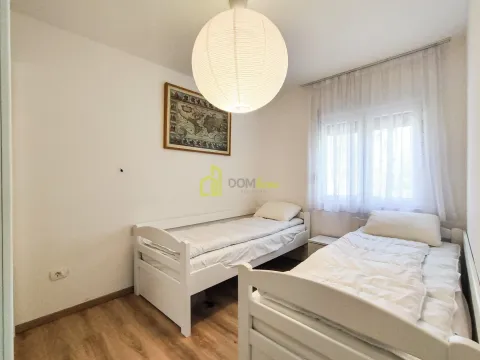 Bedroom with two white single beds and a large round ceiling lamp. - image 10