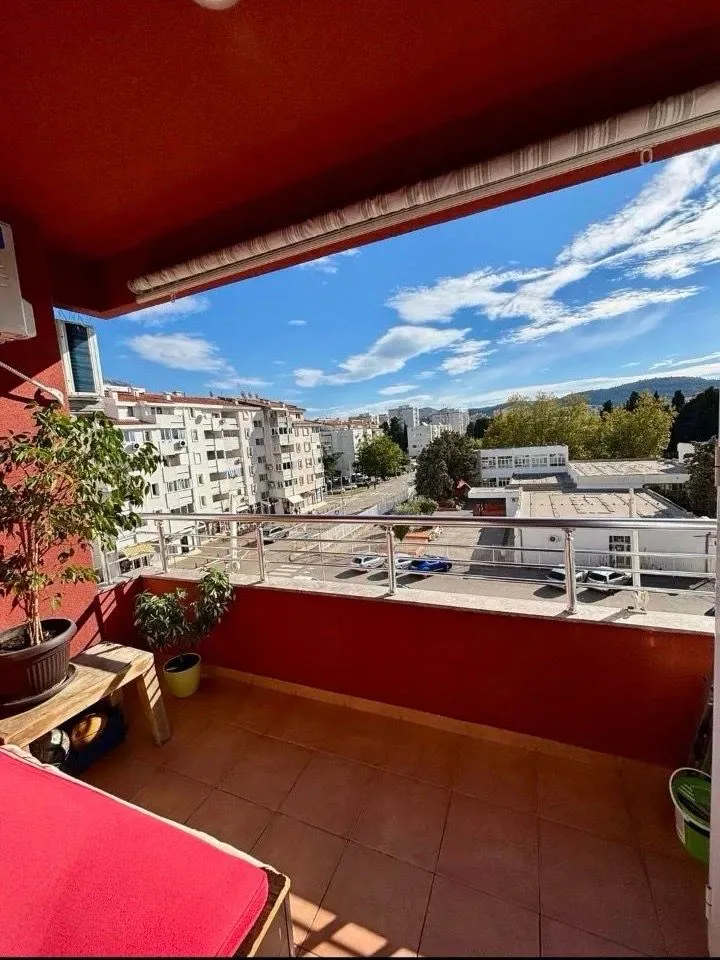 Natkriveni balkon sa pogledom na grad i okolne zgrade.