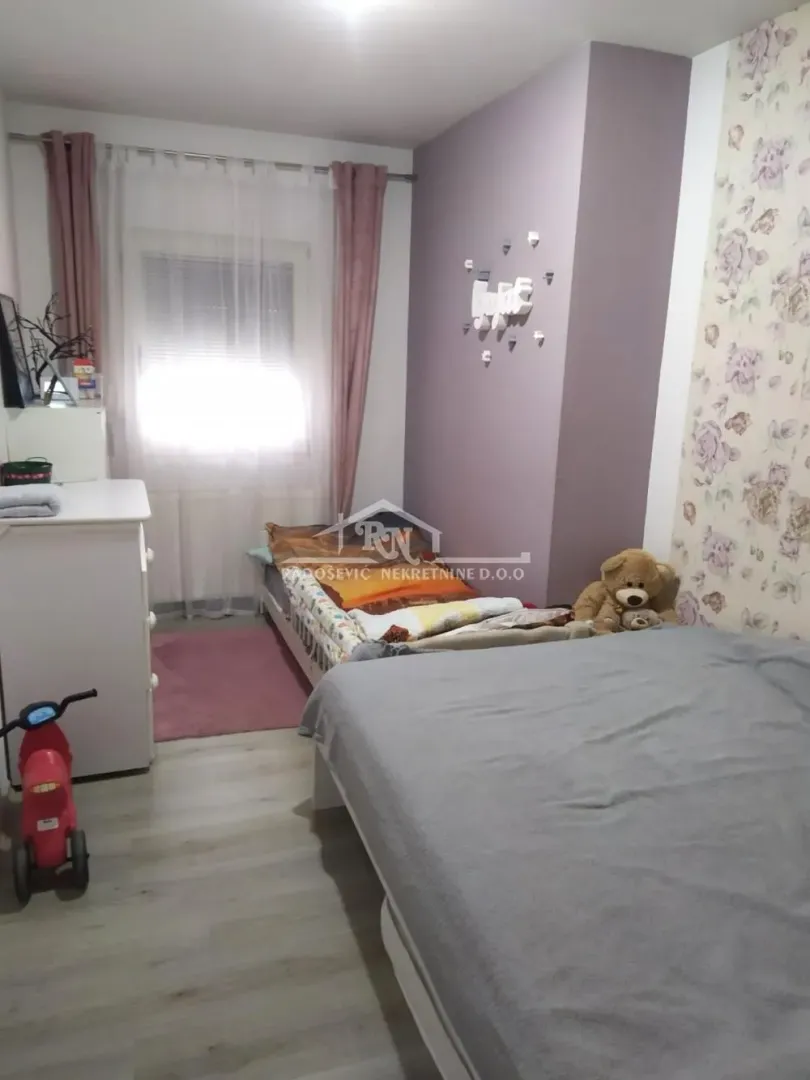 Children's bedroom with a bed, dresser, and a window with curtains.