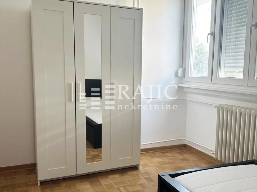 Furnished bedroom with a white wardrobe and a bed.
