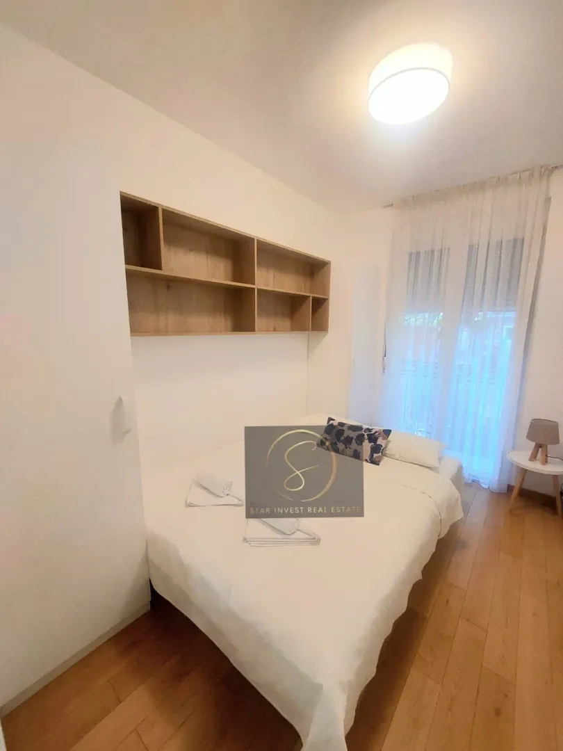Bedroom with a double bed, wooden shelves, and access to the terrace.