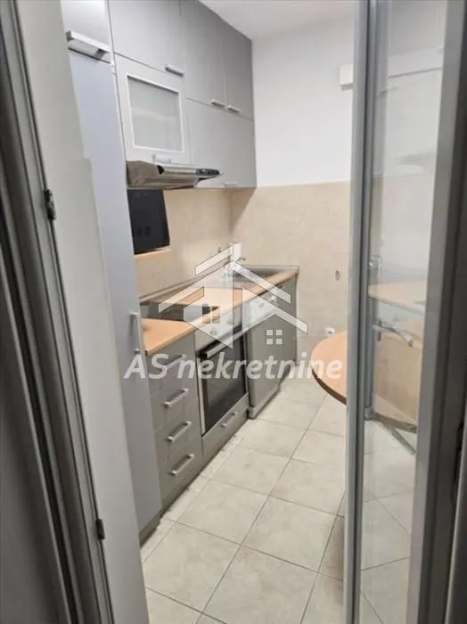 View from the hallway into a small equipped kitchen with grey cabinetry.