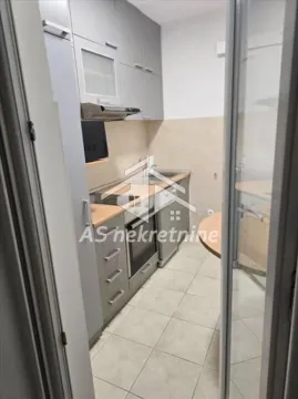 View from the hallway into a small equipped kitchen with grey cabinetry. - image 7