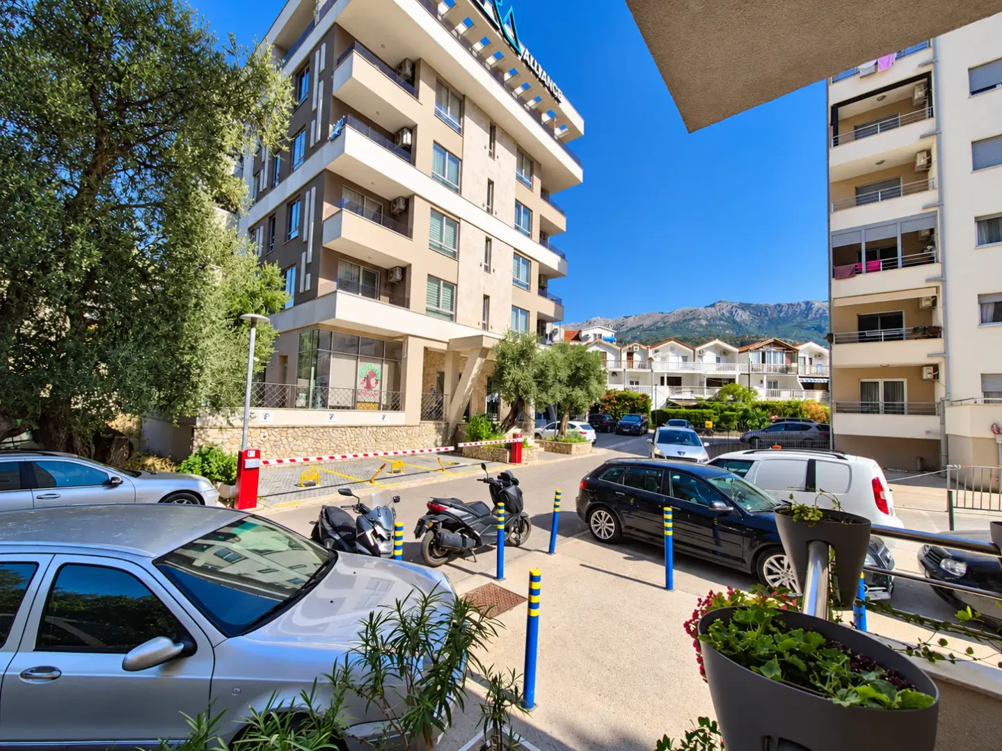 Pogled na višestambenu zgradu i parking sa parkiranim automobilima.