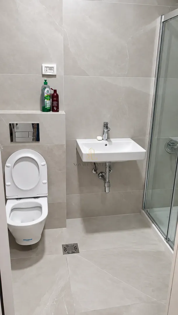 Moderne kupatilo sa tuš kabinom, umivaonikom i toaletom u svijetlim pločicama.