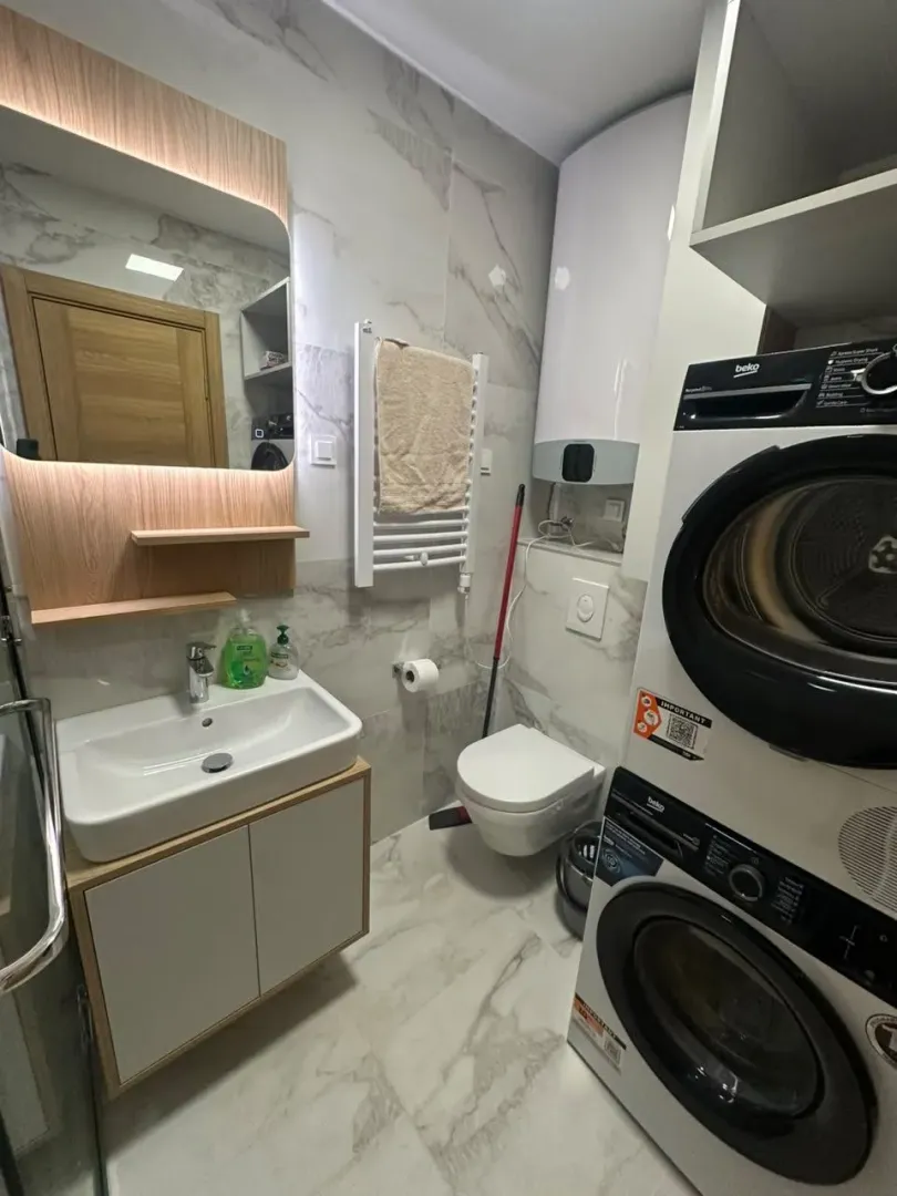 Kupatilo opremljeno umivaonikom, WC šoljom i mašinama za pranje i sušenje veša.