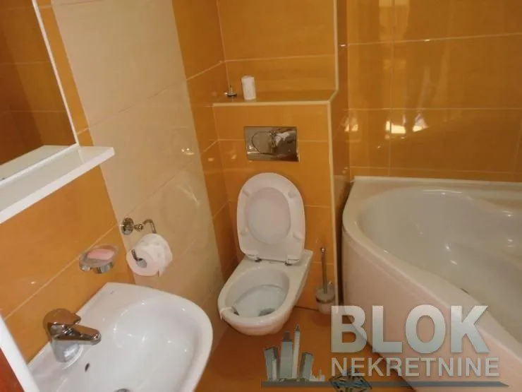 Bathroom tiled in orange with a toilet, washbasin, and bathtub.