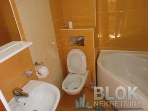 Bathroom tiled in orange with a toilet, washbasin, and bathtub. - image 4