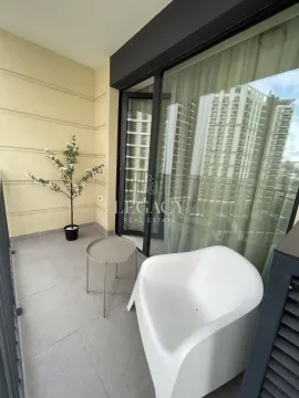 Furnished balcony with an armchair, small table, and decorative tree. - image 14
