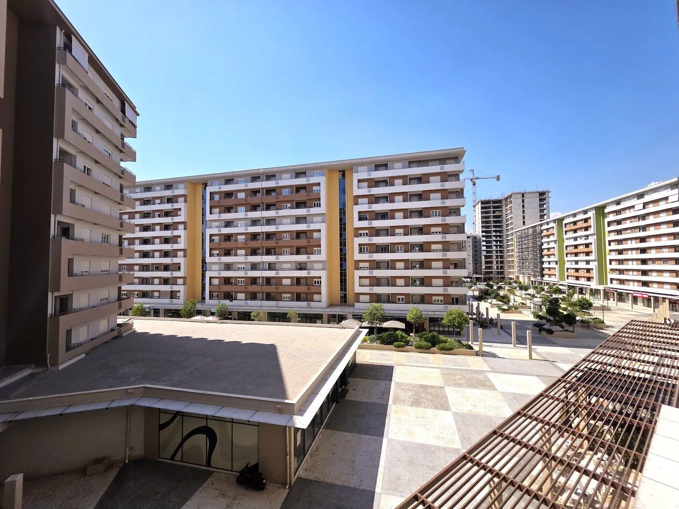 View of a modern residential complex with a landscaped courtyard and buildings.