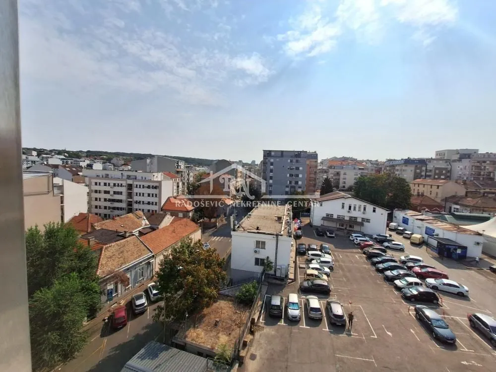 Pogled sa prozora na gradsko naselje i parking.
