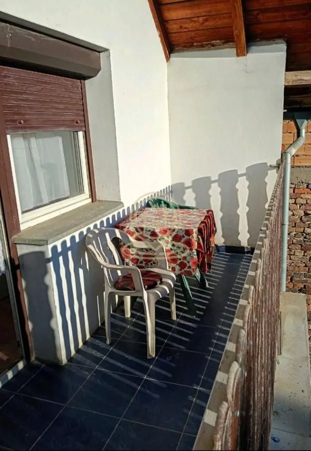 Manji natkriveni balkon sa stolom i stolicama.