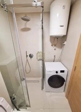 Bathroom with a shower cabin, water heater, and washing machine. - image 10