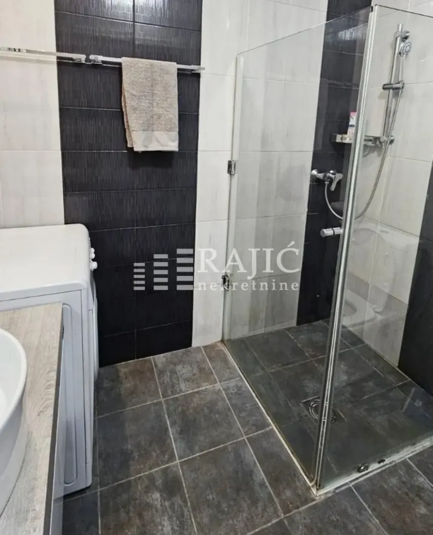 Modern bathroom with a shower cabin and white tiles.
